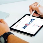 Main tenant un stylet sur une tablette affichant le site Kelnacel