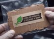 Des mains gantées tiennent un sachet de pièce à conviction contenant un carton marqué « Le meilleur produit bio et écologique au monde », avec une feuille verte.