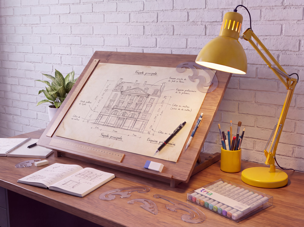 Hier : le poste du graphiste à la planche à dessin Planche à dessin inclinée avec un dessin technique de façade, stylo Rotring, lampe d'architecte jaune, feutres et perroquets sur un bureau en bois.